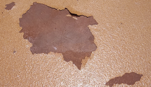 Close-up image of a coating delaminating from a concrete surface.